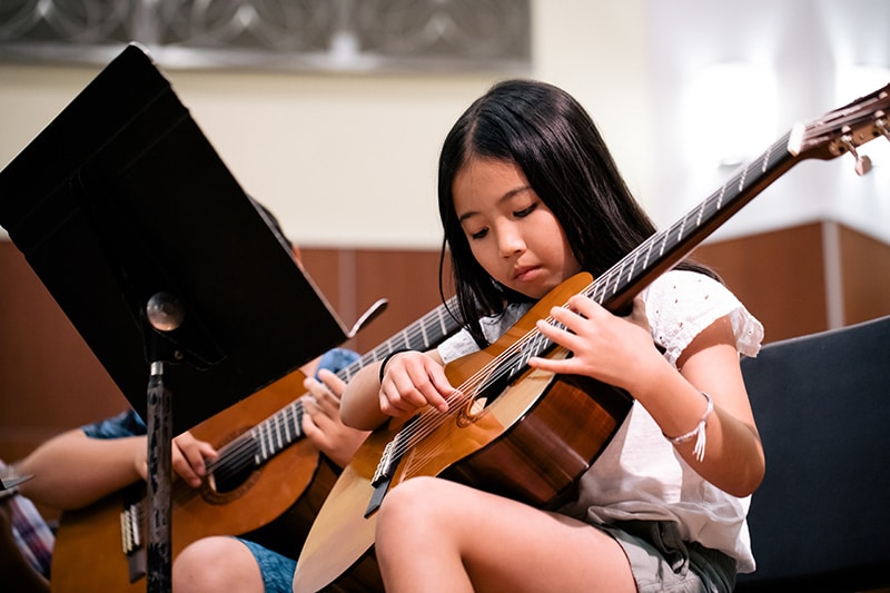 Student learning finger picking skills in a guitar class