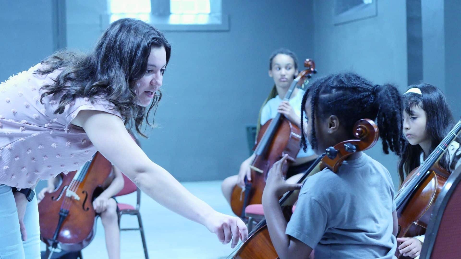 merit-south-shore-calendar A teacher helps a young cellist